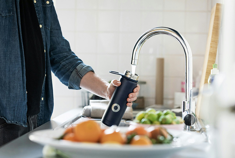 Man filling water bottle at kitchen sink